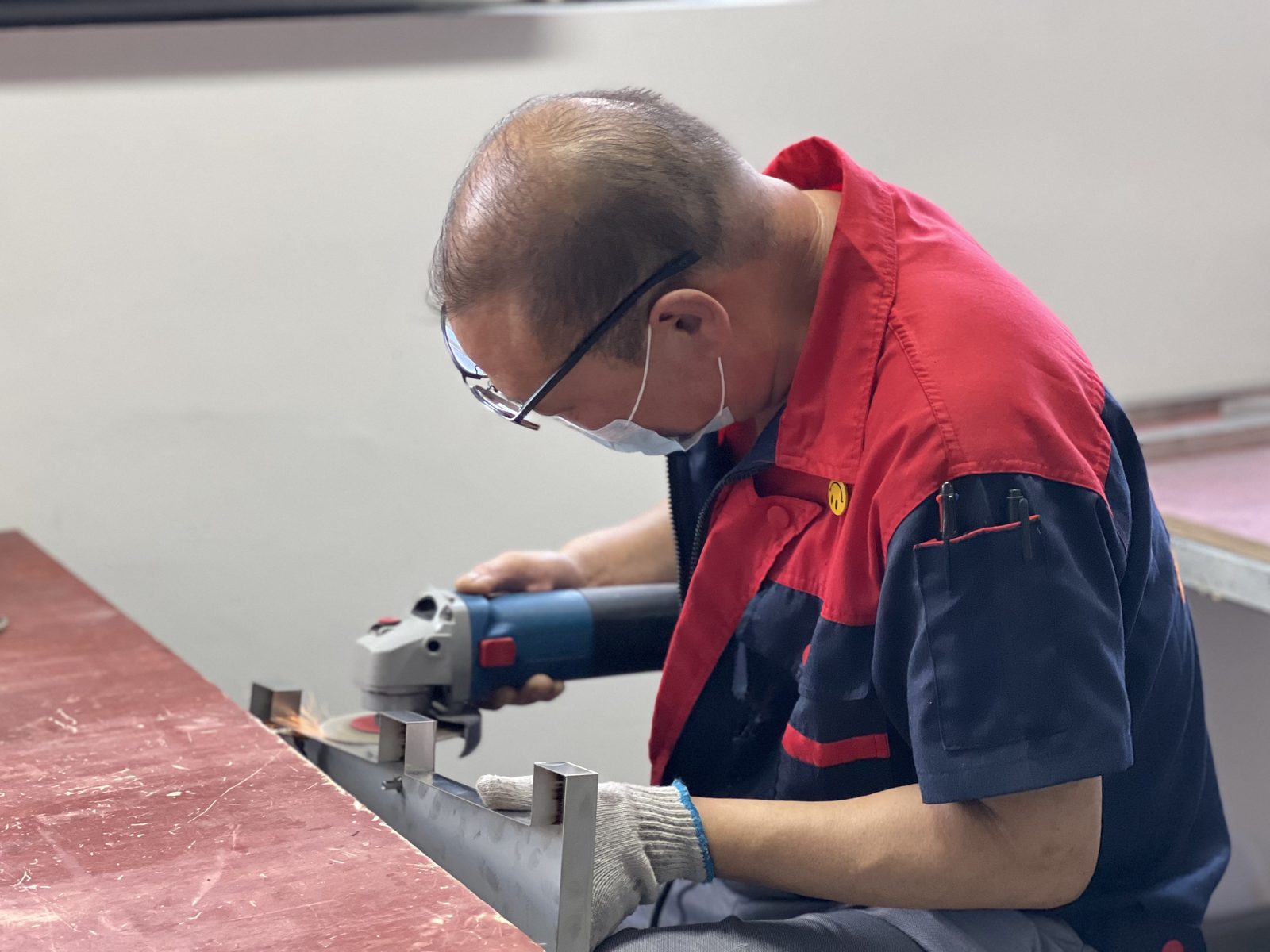 Craftsman angle-grinding a stainless steel letter shell