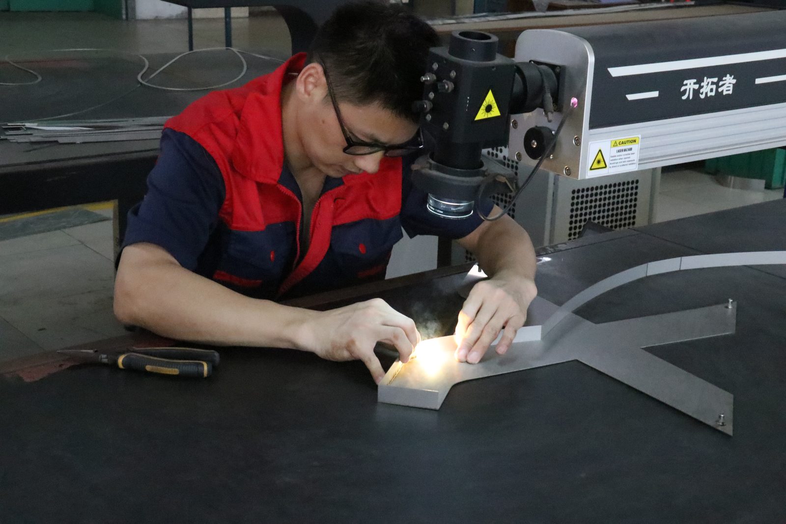 Craftsman hand-polishing a metal letter at HeFeng signs workshop